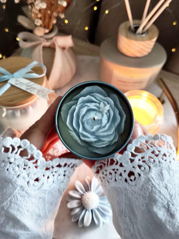Świeca sojowa w niebieskiej metalowej puszce z dekoracyjną niebieską piwonią z wosku i kokardką